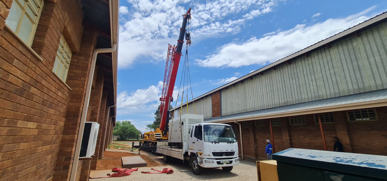 Truck-mounted crane installing a commercial standby generator